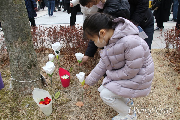  대구지하철참사 20주기 추모식이 열린 18일, 한 어린이가 추모탑 옆 희생자들의 유골이 묻혀 있는 나무 밑에 꽃을 꼽고 있다.