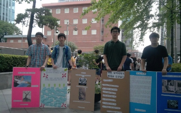 학생들이 손수 피켓을 제작해 방학 기간 일본 대사관 앞에서 <할머니들에게 명예와 인권!>을 촉구하는 피켓팅 장면이다. 학생들 너머 자주색 건물이 예전 일본대사관이다.