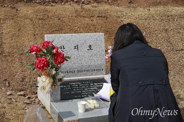 딸의 묘비앞에 앉은 어머니.