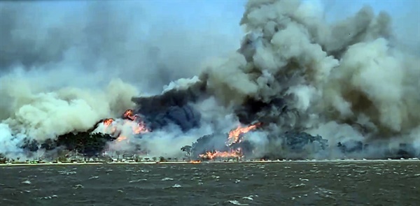 11일 오전 강원 강릉시 난곡동의 한 야산에서 난 불이 확산되는 가운데 해변가 리조트 인근에 불길이 치솟고 있다.