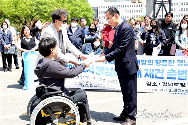 최진기 경남장애인차별철폐연대 공동대표가 28일 경남도청 정문 앞에서 강순익 경남도 장애인복지과장한테 건의문을 전달하고 있다.