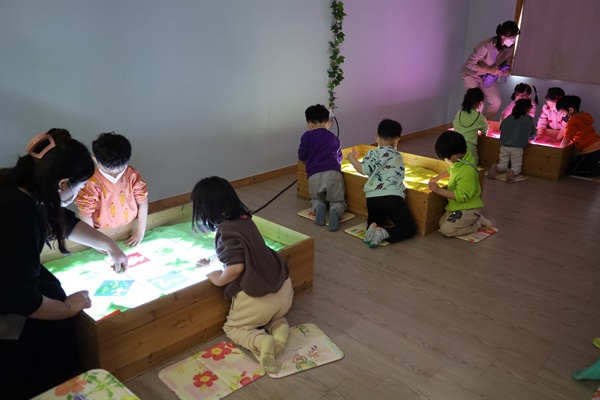 아이들이 빛과 모래방에서 체험놀이를 하고 있다