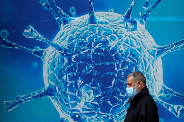 보호용 마스크를 쓴 한 남성이 지역 과학 센터 밖의 바이러스 그림 앞을 지나가고 있는 모습(자료사진)