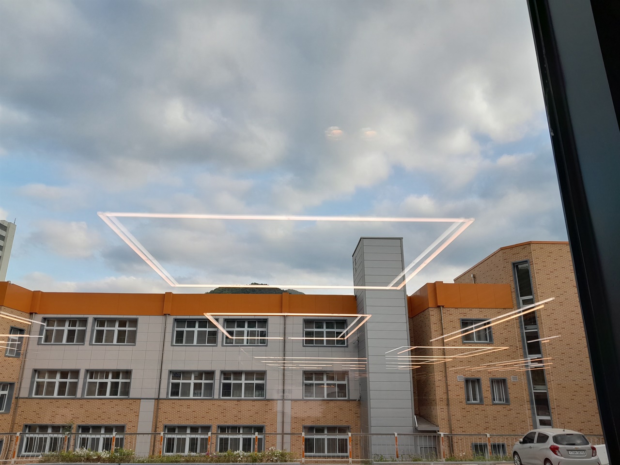 도서관 내 대형 유리창에 특색 있는 도서관의 조명시설이 비친 모습. 앞 건물은 상진초등학교이다.  