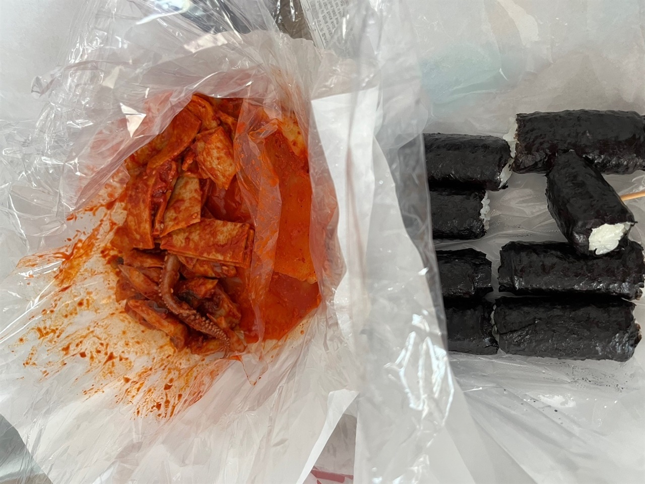 흰 종이로 차려진 오뎅과 무김치와 김밥 한상.
