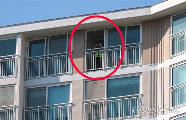 금속노조 경남지부가 5월 31일 오후 창원 만남의광장 앞에서 집회를 열었을 때 건너편 아파트 꼭대기층에서 경찰관이 캠코더로 촬영하고 있다(원안).