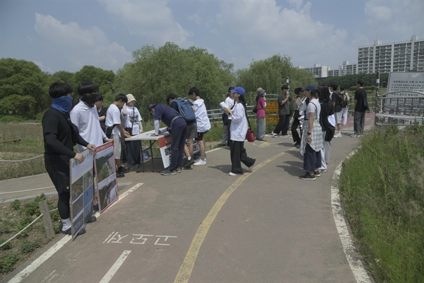 팔현습지 강촌햇살교 앞 산책로 한편에서 서명운동을 벌이고 있는 간디학교 학생들