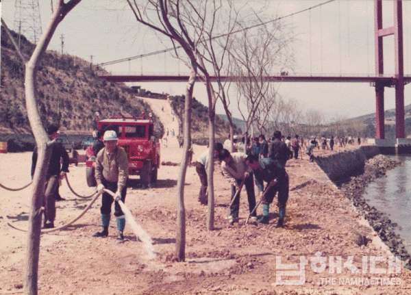  주변 경관 조성을 위해 식수 중인 사람들 뒤로 남해대교가 보인다.