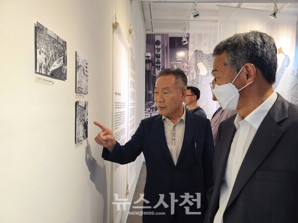  유월 민주항쟁 36주년 경남 서부지역 기념식과 전시회에 참석한 이영주 전 경남교육연구정보원장과 오태열 사천중앙교회 담임목사가 옛 사진을 보며 이야기를 나누는 모습.