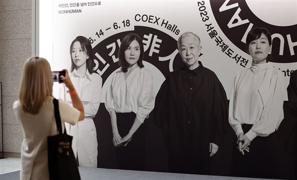 14일 서울 강남구 코엑스에서 열린 2023 서울국제도서전에서 한 관람객이 홍보대사 포토월을 촬영하고 있다. 포토월 속 왼쪽에서 세 번째가 오정희 작가.  