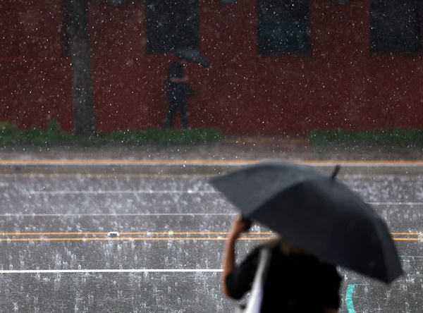 소나기가 내린 14일 오후 서울시내에서 시민들이 우산을 쓴 채 이동하고 있다.