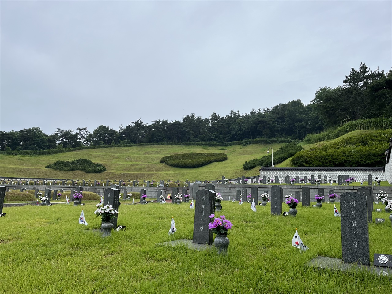  국립 5.18 민주 묘지의 10구역 모습. 봉분이 없고, 묘비의 이름 아래 '묘' 대신 '령'이라고 적혀있다. 그 너머로 봉분이 있는 묘가 줄지어 있는 모습이 보인다.