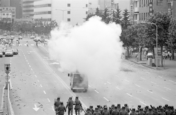 1987년 6월 10일 항쟁 국민대회. 시위대가 광화문을 향해 행진하며 데모를 벌이자 전경들이 페퍼포그를 발사, 해산시키고 있다.
