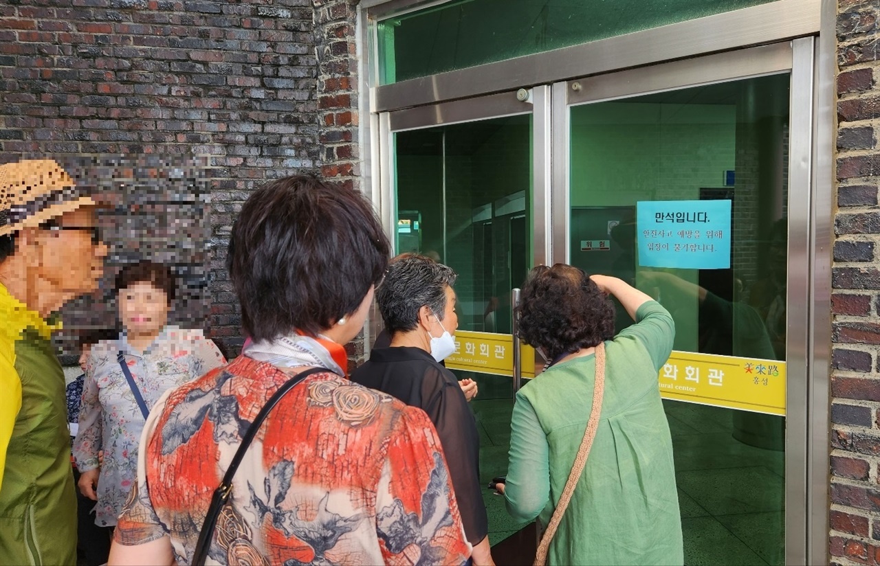 공연을 보기위해 홍주문화회관을 찾은 어르신들이 잠긴 문 앞에서 안을 들여다 보고 있다.