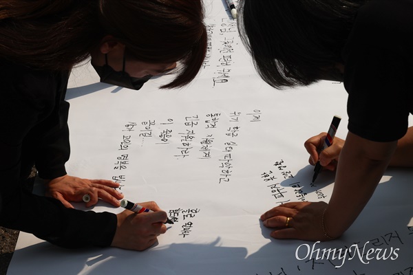 20일 오후 서울시교육청앞에서 전교조 조합원들이 학교에서 사망한 채 발견된 서초구 S초등학교 교사를 추모하는 글을 흰 천에 적고 있다.