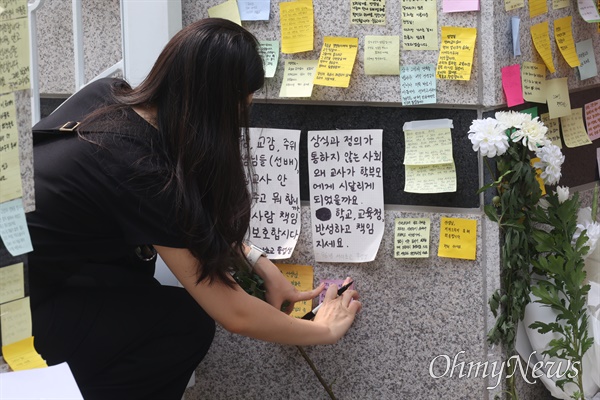 시민들이 20일 오후 서울 서초구 S초등학교 앞에서 1학년 교사의 죽음에 가슴 아파하며 애도의 메시지와 국화꽃을 놓고 있다.