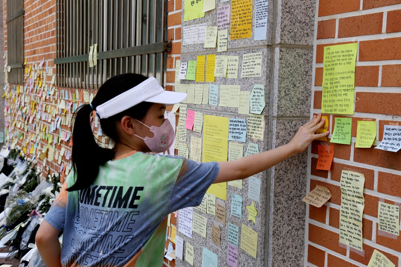 한 초등학생이 메모지에 숨진 S초등학교 교사를 추모하는 글을 적어 벽에 붙이고 있다.
