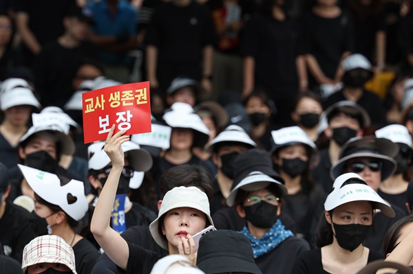 서울 서초구의 한 초등학교에서 발생한 교사 사망 사건과 관련해 22일 오후 서울 종로구 보신각 인근에서 열린 추모식에서 한 참가자가 손팻말을 들고 있다. 