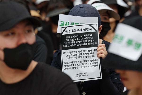 서울 서초구의 한 초등학교에서 발생한 교사 사망 사건과 관련해 22일 오후 서울 종로구 보신각 인근에서 열린 추모식에서 한 참가자가 전국 초등교사 성명서를 들고 있다.