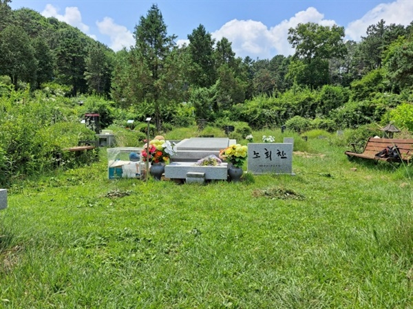 경기도 마석 모란공원에 있는 노회찬 의원 묘소. 7월 둘째 주 어느 젊은 여성이 옆 벤치에 가방을 내려 놓은 채, 무더위 속에 노회찬 의원 무덤 주위를 정돈하고 있다. 