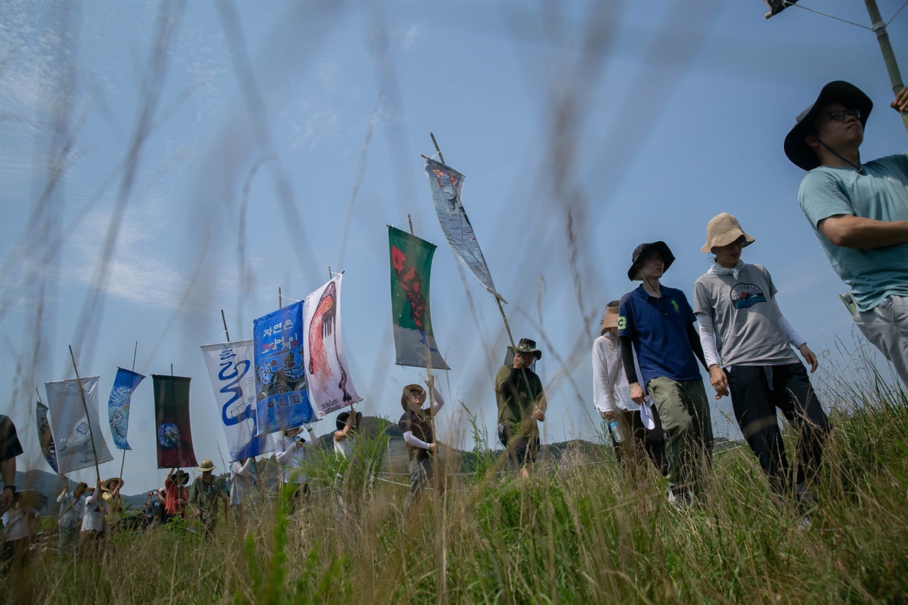 참가자들이 다양한 그림이 그려진 만장을 들고 해창갯벌 장승벌을 걷고 있다.