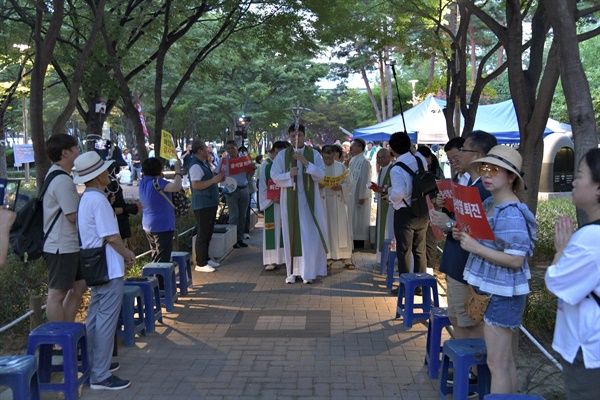 시민들이 양옆으로 도열한 가운데 정의구현전국사제단이 미사 봉헌을 위해 입장하고 있다. 