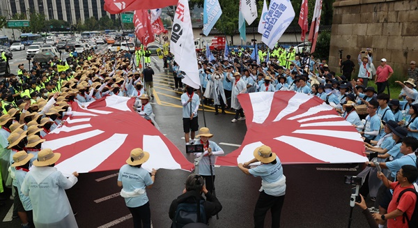 지난해 8월 11일 오후 서울 종로구 일본대사관 인근에서 전국민중행동 통일선봉대가 연 '후쿠시마 오염수 방류 반대 집회'에서 참가자들이 욱일기를 자르는 퍼포먼스를 하고 있다.