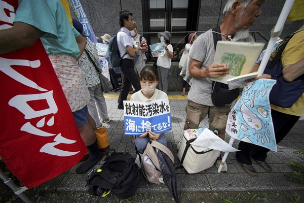 2023년 8월 24일 도쿄의 도쿄전력 본사 건물 밖에서 일본 정부의 후쿠시마 제1원전 처리 오염수 해양 방류 계획에 반대하는 집회가 열렸다. 한 참가자가 "방사능 오염수를 바다에 버리지 마라!"라고 적힌 팻말을 들고 있다.