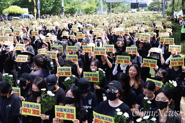 전국에서 모인 교사들이 2일 오후 2시 서울 영등포구 국회의사당 앞에서 열린 '50만 교원 총궐기 추모집회'에 참석해 국화와 "아동복지법 즉각 개정"이라고 적힌 피켓을 들고 있다.