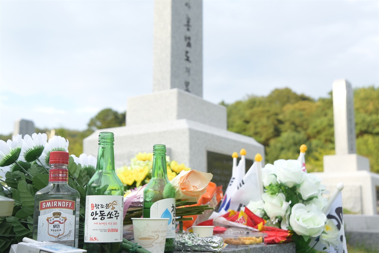 홍범도 장군 묘 앞에 많은 사람들이 놓고 간 꽃과 술, 음식들이 놓여 있다.