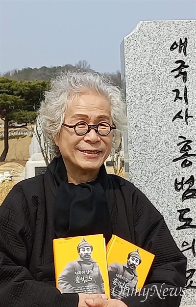 홍범도 장군의 평전을 펴낸 이동순 교수가 홍 장군의 묘역 앞에서 책을 들고 사진을 찍었다.