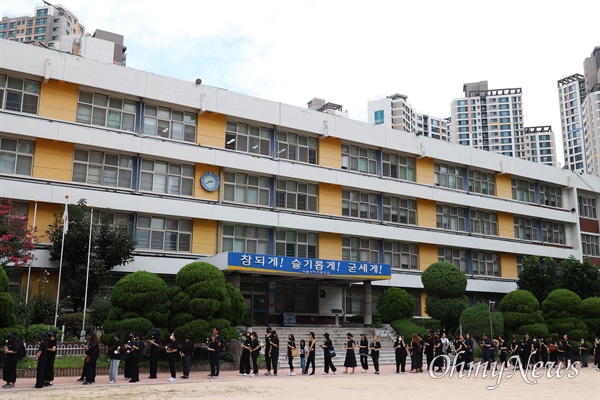  서이초 교사 49재를 맞은 4일 오후 서초구 서이초에서 교사와 시민들이 교실과 가까운 곳에 마련된 추모장소에 헌화하기 위해 길게 줄을 서 기다리고 있다.