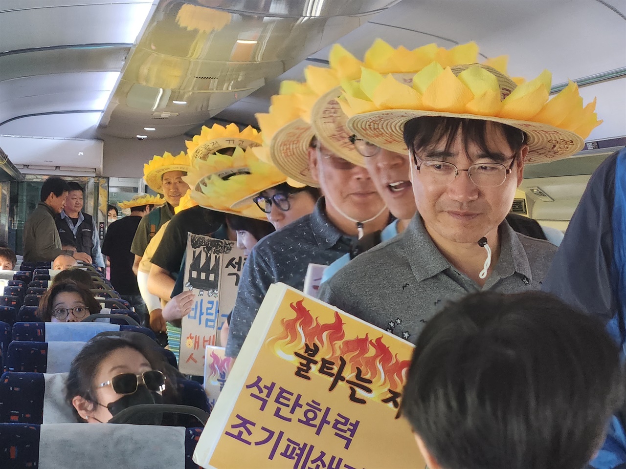 기후정의 열차에 탄 충남도민들, 머리에 햇빛을 상징하는 밀집모자를 쓰고 있다. 