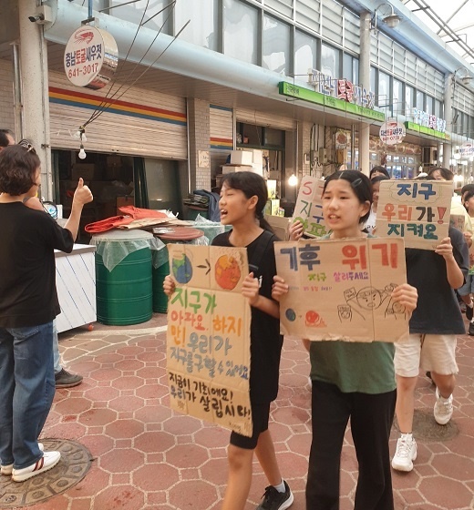 충남 홍성 광천 시장에서 캠페인을 벌이고 있는 장곡초 어린이들.  한 시민이 엄지손가락을 들어 올리며 아이들을 응원하고 있다. 