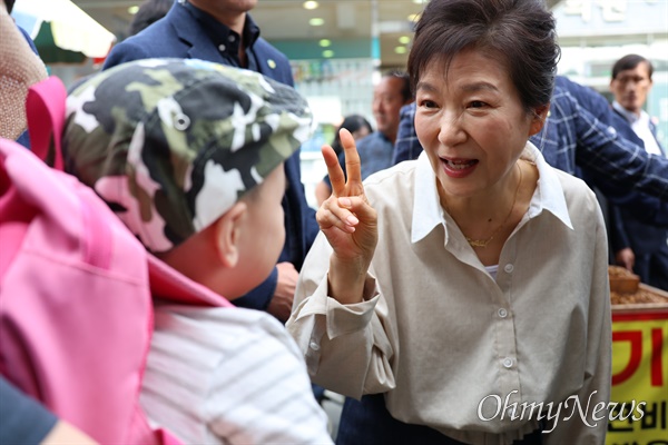 전직 대통령 박근혜씨가 추석을 앞두고 25일 오전 자신의 집 근처인 현풍시장을 찾아 엄마 품에 안긴 아이의 나이가 2살이냐며 손가락으로 2를 가리키고 있다.