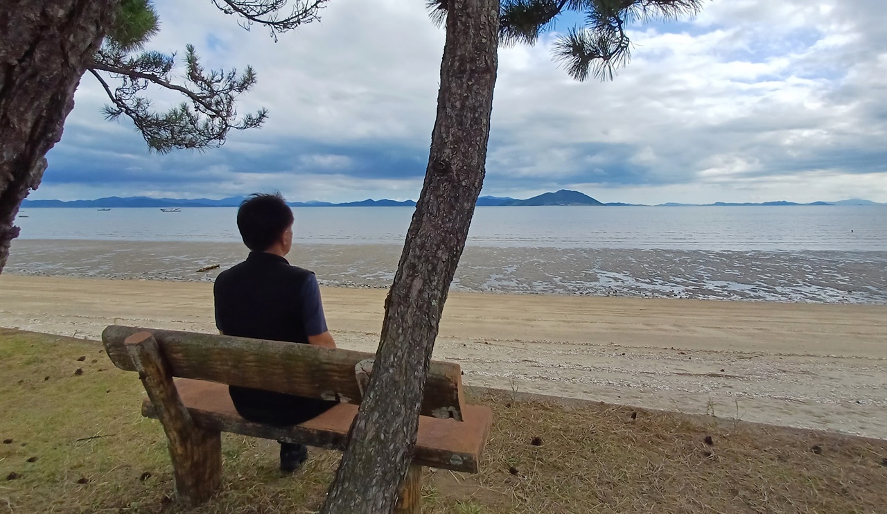 명교해변 풍경. 마을주민이 나무의자에 앉아 득량만을 바라보며 쉬고 있다.