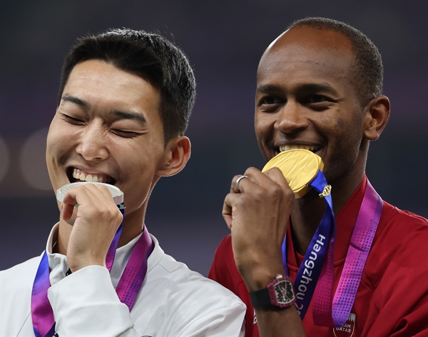  4일 중국 항저우 올림픽 스포츠센터에서 열린 2022 항저우 아시안게임 남자 높이뛰기 결선에서 2m33을 넘으며 은메달을 차지한 우상혁이 시상대에 올라 금메달을 딴 카타르의 무타즈 에사 바르심과 기념사진을 찍고 있다. 2023.10.4