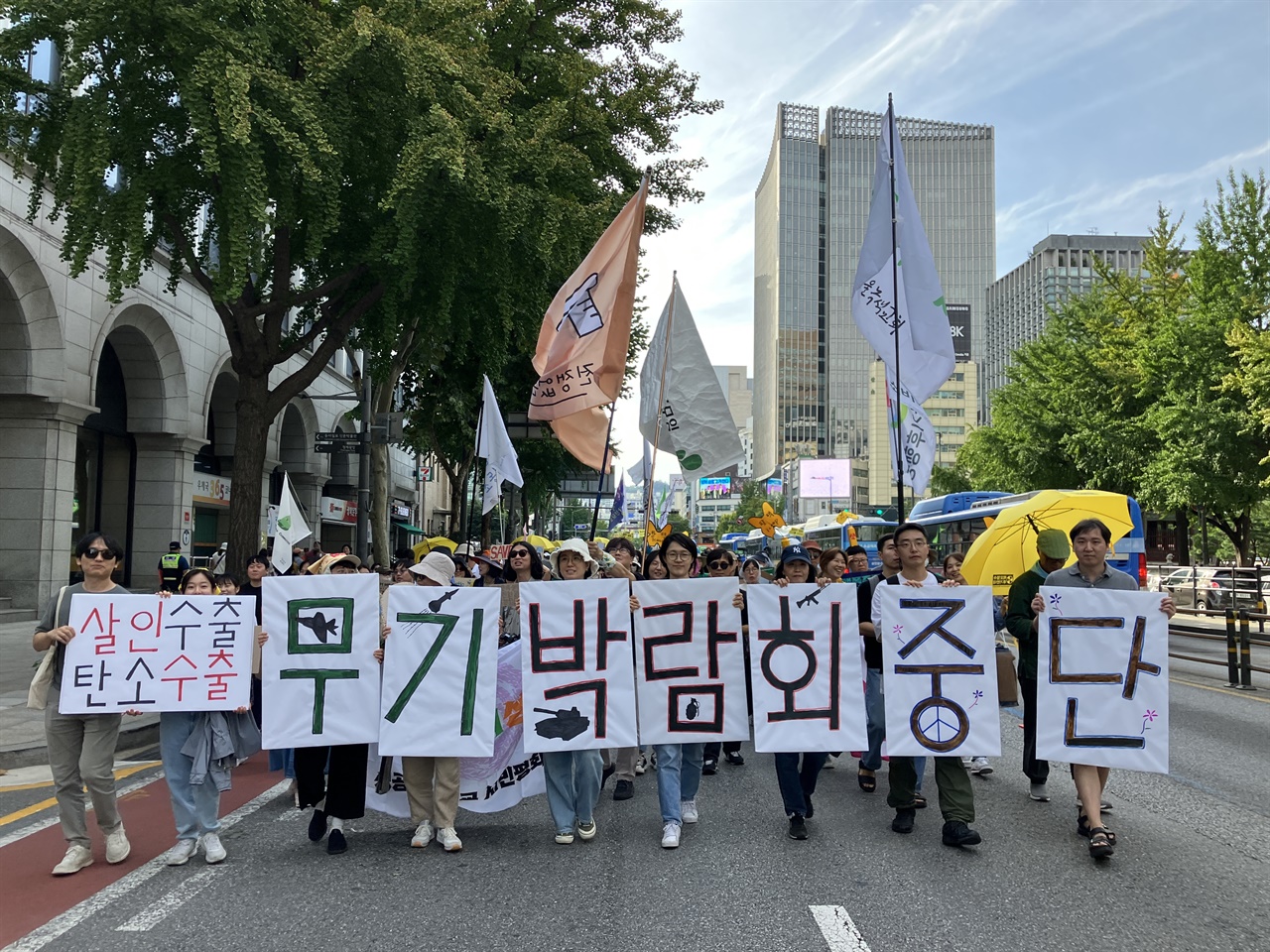 평화활동가들이 지난 9.23 기후행진에서 “평화파괴, 기후파괴 무기박람회 중단”이라고 쓰인 피켓을 들고 행진하고 있다.