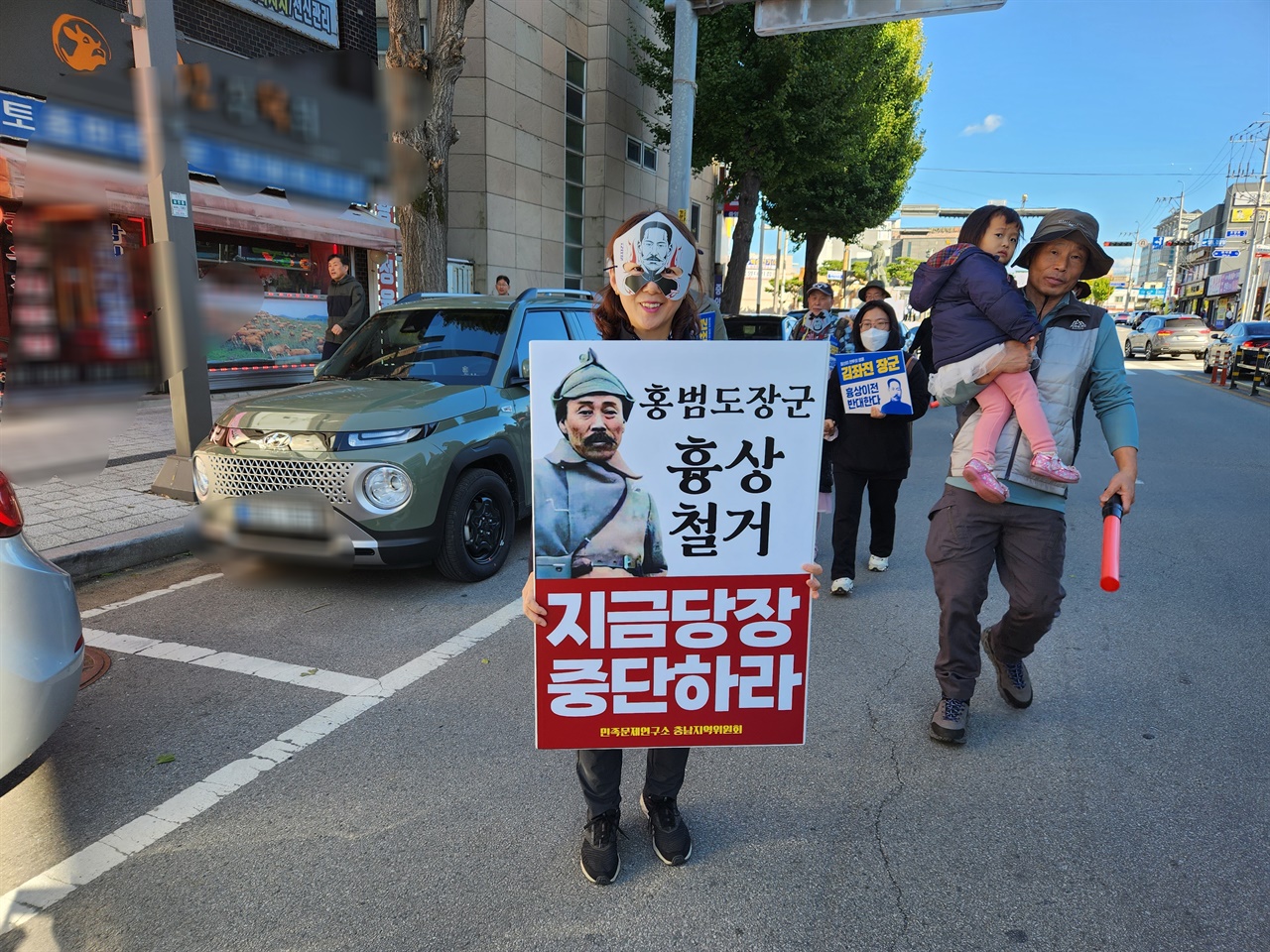 김좌진 장군의 가면을 쓴 시민이 '홍범도 장군 흉상 철거, 지금당장 중단하라'고 적힌 피켓을 들고 있다.  