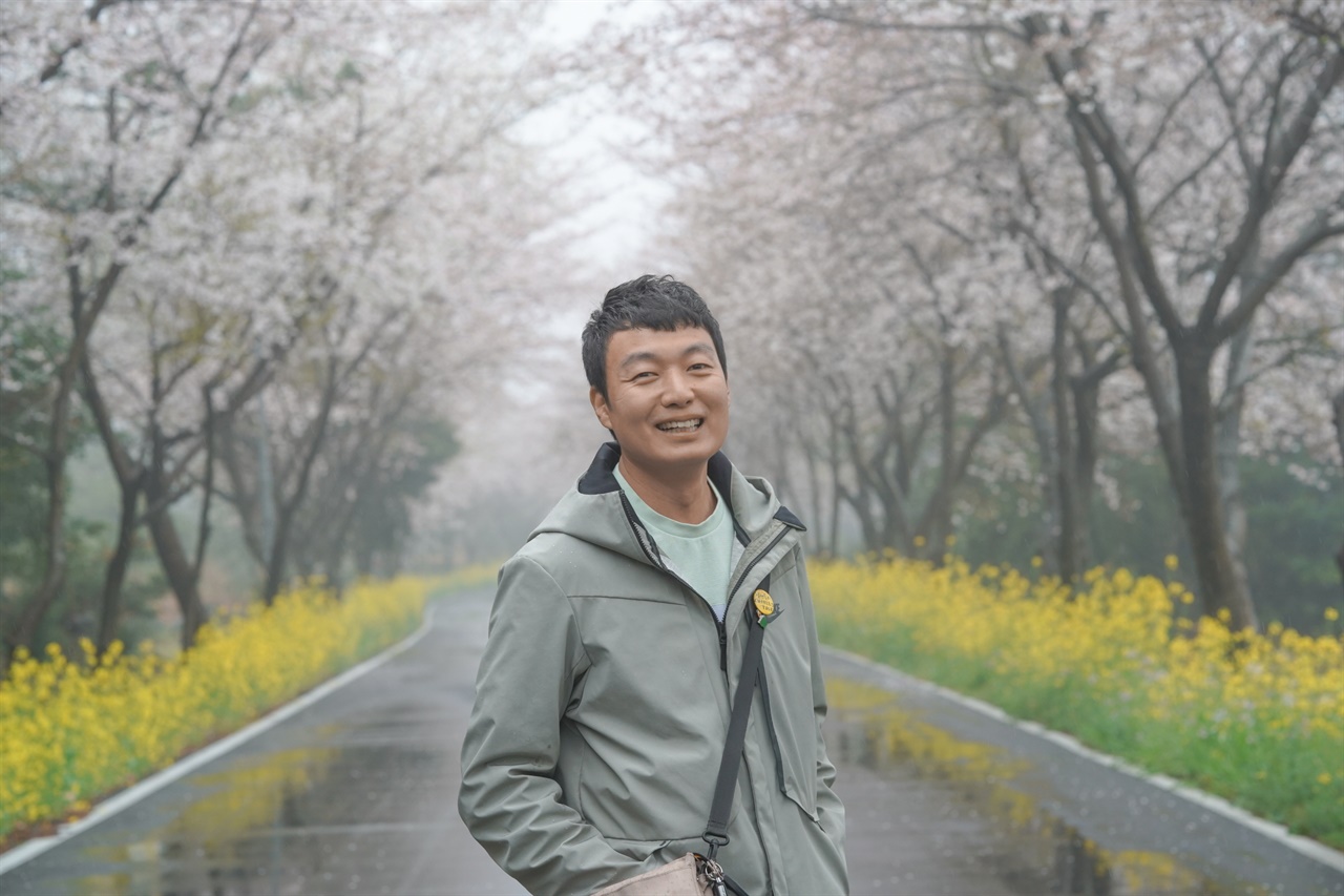 벚꽃과 유채꽃이 만발한 길에서 제주도 1인 여행사를 운영하고 있는 양성철씨가 환하게 웃고 있다.