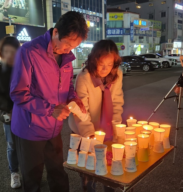 이태원 참사 유가족들이 희생자들을 추모하기 위해 마련한 촛불에 불을 붙이고 있다.