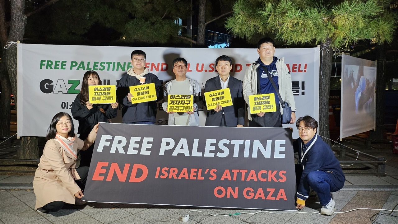 참가자들이 “이스라엘 지원하는 미국 규탄!” “GAZA에 평화를! GAZA에 자유를!” “이스라엘 가자 지구 공격 규탄” 피켓을 들고 있다. 