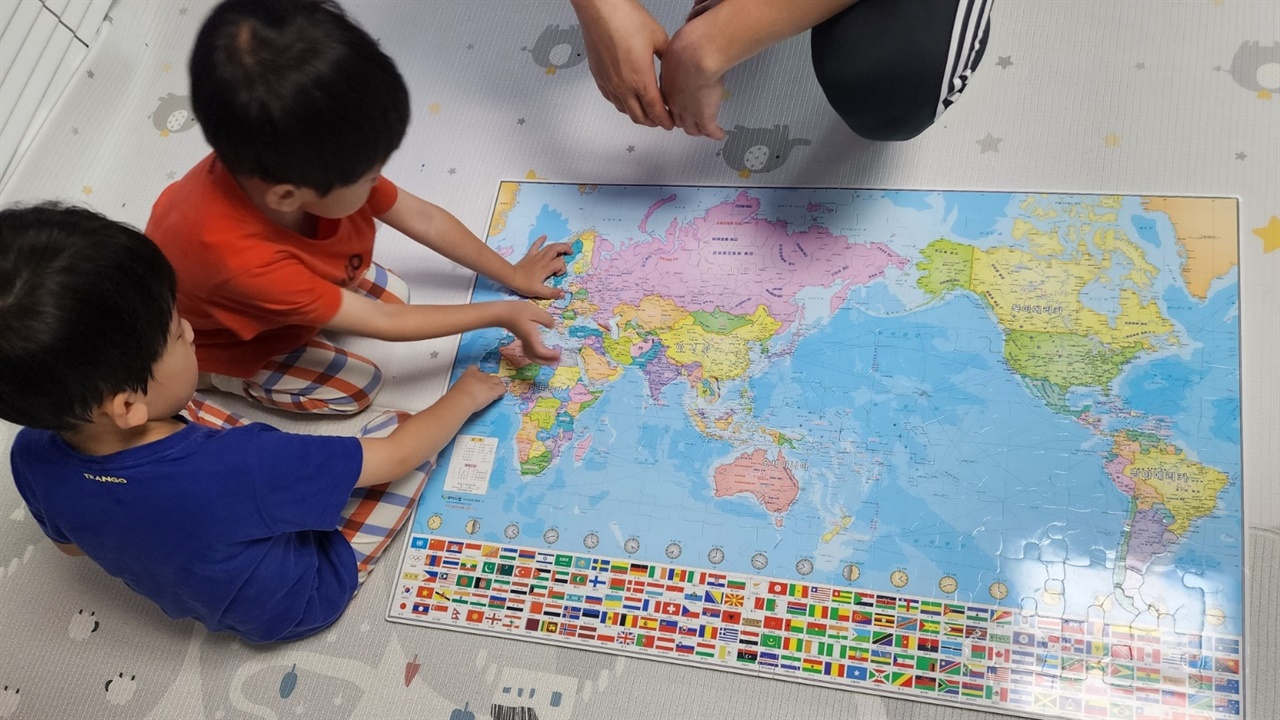 세계 여러나라와 국기에 관심이 있는 쌍둥이 손자와 지도 퍼즐을 맞추고 있다.