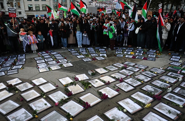 2023년 11월 4일 영국 런던에서 열린 '지금 당장 휴전' 집회에서 시위대가 트라팔가 광장에 놓인 팔레스타인 어린이 사망 사진 옆에 팔레스타인 국기를 들고 가자지구의 휴전을 촉구하고 있다.