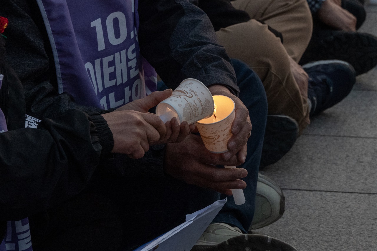 풍남문광장 앞 이태원 참사 추모제에서 시민들이 서로의 초에 촛불을 붙여 주고 있다.