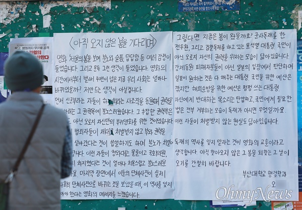 13일 부산대학교 자연대 건물 앞 학생게시판에 이틀째 게시된 '서울의 봄 대자보'. 지나가던 시민이 이를 유심히 지켜보고 있다.
