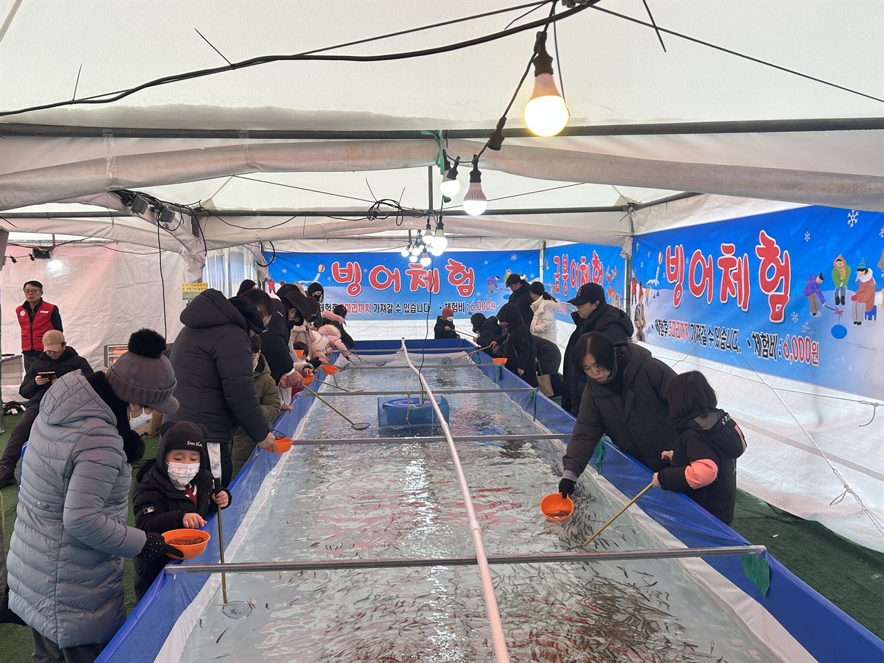 겨울테마파크에서 방문객들이 빙어잡기 체험을 하고 있다. 