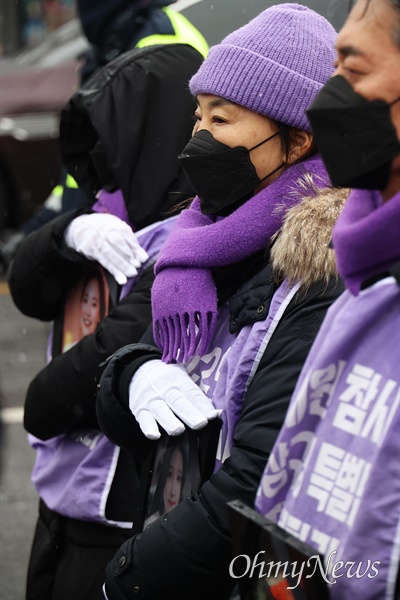 행진에 참여한 유가족들이 영정사진이 눈에 젖지 않게 하기 위해 손으로 가리고 있다.