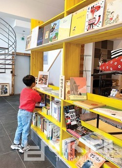 한 어린이가 어린이 책 코너에서 책을 고르고 있다.