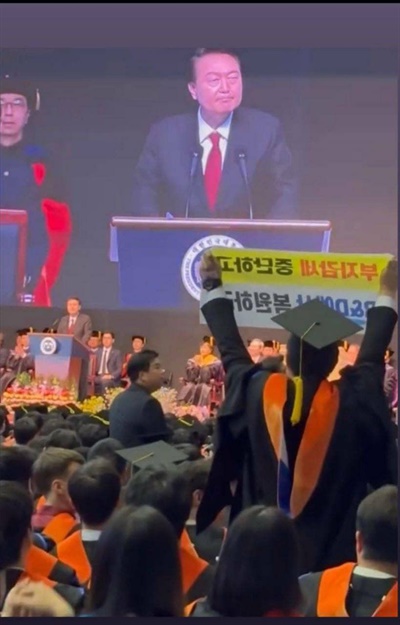 6일 대전 유성구 한국과학기술원(KAIST)에서 열린 2024년 학위수여식에서 한 졸업생이 윤석열 대통령이 축사를 할 때 R&D 예산과 관련해 자리에서 일어나 대통령을 향해 항의하고 있다. 해당 졸업생은 이후 퇴장당했다.